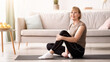 © Prostock-studio - Happy senior woman resting on yoga mat after training, looking at camera at home, free space. Active mature lady taking break after domestic fitness or yoga, leading healthy lifestyle