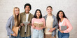© Prostock-studio - Facial expressions and emotions of student team. Excited laughing young multiracial people with open mouths hold books and gadgets and look at camera on white wall background, studio shot, empty space