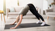 © Prostock-studio - Domestic yoga practice. Flexible mature lady standing in downward facing dog asana, exercising on sports mat at home. Athletic senior woman working out indoors during coronavirus lockdown