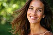 © starush - A woman with long brown hair smiling outdoors in natural sunlight
