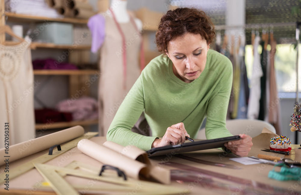 Woman tailor creates sketch of dress on tablet, draws and visualizes ...