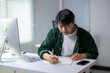 © Wasana - A man is sitting at a desk with a notebook and a pen