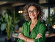 © Havoc - Portrait of a smiling woman with curly hair wearing glasses and a green shirt with arms crossed