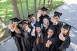 © Михаил Решетников - Students of different nationalities in graduation gowns give thumbs up.