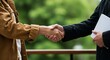 © Sayam - Two business professionals firmly shaking hands outdoors in a show of agreement and partnership with a blurred green background