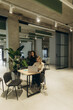 © Roman - Two Colleagues Collaborate in a Modern Office Environment with a Laptop