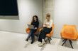 © Roman - Two Women Collaborate in Modern Office Seated on Stylish Orange Chairs