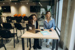 © Roman - Two Women Colleagues Working Together in a Modern Office Setting