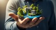 © Zaldy - A man holds a miniature world with buildings, trees, and water in his hand, symbolizing environmental responsibility.