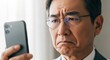 © Stingray_Japan - 落選の瞬間：スマホの画面を見てがっかりする60代日本人男性