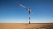 © Sukatno - Construction crane stands alone against a clear blue sky in a desolate landscape