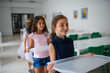 © Halfpoint - Kids in school canteen waiting for lunch, holding tray.