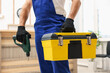 © New Africa - Professional repairman with tool box and electric screwdriver indoors, closeup