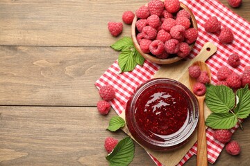 Wall Mural - Tasty jam, fresh ripe raspberries and leaves on wooden table, flat lay. Space for text