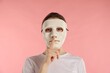 © New Africa - Anonymity. Woman wearing mask and showing hush gesture on pink background