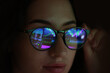 © New Africa - Young woman wearing glasses with reflection on dark background, closeup