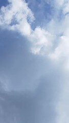 Wall Mural - Vertical orientation timelapse showing cumulus clouds forming and expanding against a bright blue sky, with distinct white tops and subtle shadowing as they evolve in daylight.