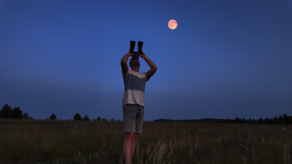 Wall Mural - amateur astronomer using binoculars for watching stars, moon, planets and other celestial objects fr