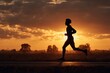 © Tarakan - Silhouette of a runner at sunset.  A person in silhouette runs on a road as the sun sets, casting a warm glow on the clouds and landscape