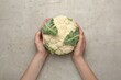 © New Africa - Woman with whole cauliflower at light table, top view