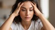 © helga - A concerned young woman with her hands on her head, looking down with a worried expression, indoors, considering problems.