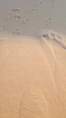 minimalist top down view of human footprints on a rippled sand dune. natural abstract background con
