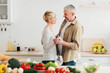© Prostock-studio - Fun, happy and dating together, relationships in middle aged. Cheerful senior couple dancing on cozy kitchen interior with bright vegetables and glasses of wine, empty space
