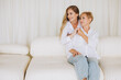 © anatoliycherkas - Mother and Daughter Sharing a Moment of Affection on a White Sofa