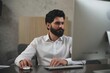 © Premium Resource - Man working on computer in office, professional using desktop pc for business tasks, office work