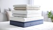 © affan - A stack of various mattresses and mattress toppers sits on a bed in a bright room