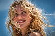 © Prasanth - Radiant young woman with blond hair smiles brightly against clear blue sky. Bright sunshine illuminates face, emphasizing youthful beauty, joyful expression. Enjoys warm summer day outdoors, exuding