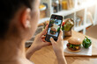 © Bithi - Woman photographing burger with smartphone in kitchen