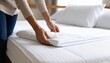 © Rupa - A woman's hands carefully placing a fresh white quilted mattress protector on a bed.