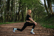 © dsheremeta - Athletic woman stretching legs in forest trail: embracing nature's gym