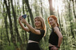 © dsheremeta - Women exercising outdoors and taking selfie in forest