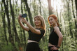 © dsheremeta - Two fit women taking selfie after workout in forest