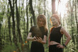 © dsheremeta - Two women checking fitness app on smartphone while training outdoors in forest