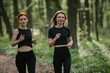 © dsheremeta - Two women jogging in a lush forest path