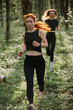 © dsheremeta - Energetic women running through forest trail