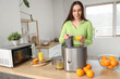 © Pixel-Shot - Young woman making orange juice at table in kitchen