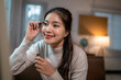 © Wasana - Smiling asian woman applying mascara at home