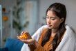 © Wasana - Sick young woman taking pills at home on sofa covered with blanket