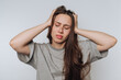 © bodnarphoto - portrait of young frustrated woman holds her head in both hands, depicting clear signs of stress on light background