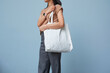 © Ton Photographer4289 - Young woman with holding tote bag for mockup design on blue color wall background. Environment friendly shopping handbag.