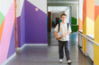 © Serhii - Student walking in colorful school hallway holding books