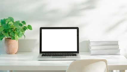 Wall Mural - Laptop with blank white screen on a minimalist desk, decorated with a potted plant.