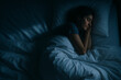 © IBEX.Media - Young woman peacefully sleeping in bed at night, wrapped in soft white bedding under a gentle, moody light