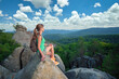 © bilanol - Hiker girl resting on rocky mountain top enjoying summer nature during her travel on wilderness trail. Lonely female traveler traversing high hilltop route. Healthy lifestyle concept