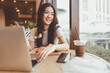© dodotone - Happy smile asian woman eating croissants at cafe sitting near window indoors on day