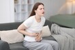© New Africa - Young woman suffering from stomachache at home